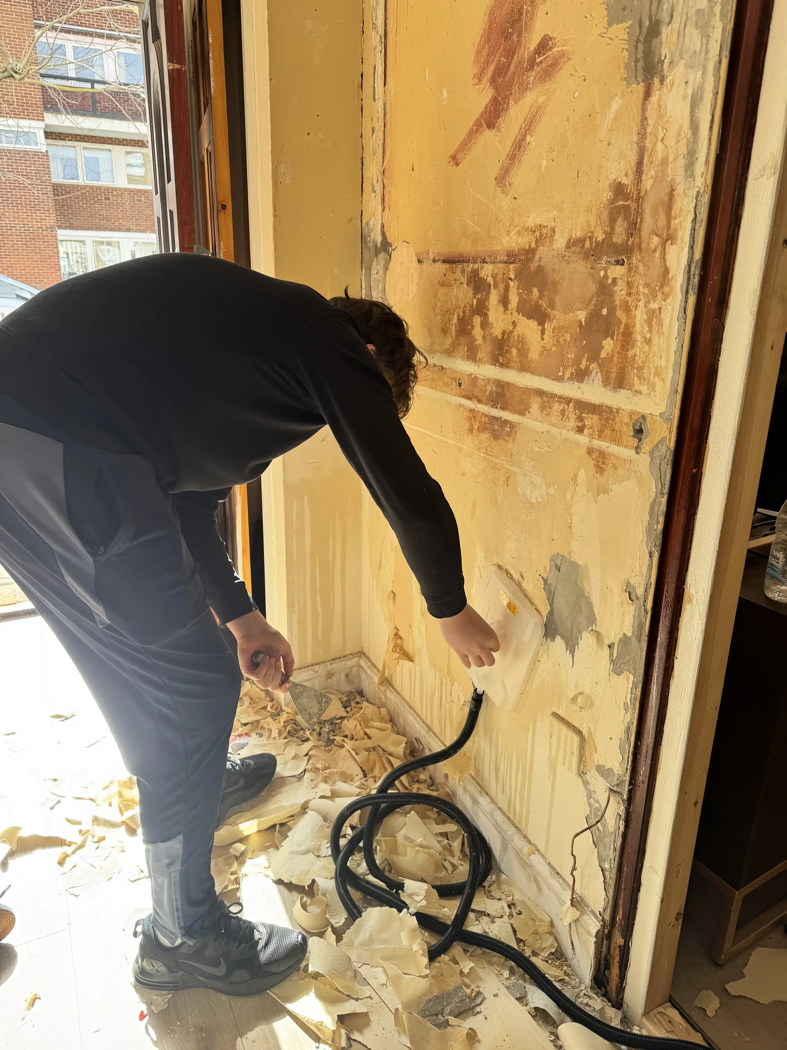 Community Heroes volunteer steam-stripping wallpaper